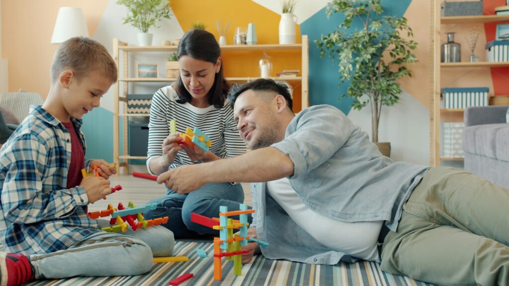 Eltern und Kind räumen gemeinsam Spielzeug in beschriftete Kisten