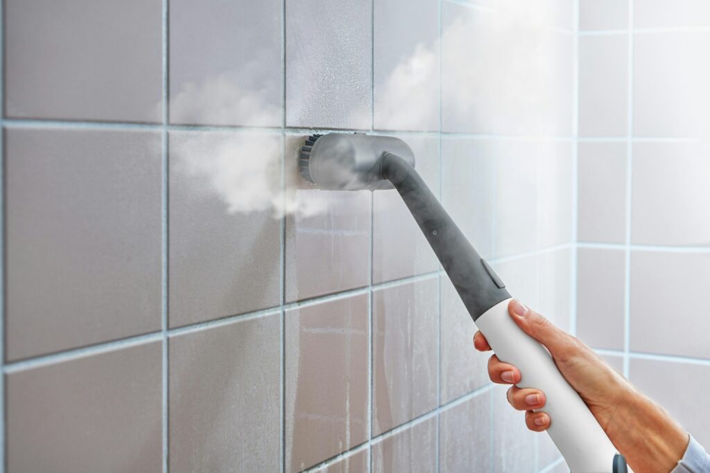 Dampfreiniger reinigt eine geflieste Wand im Bad
