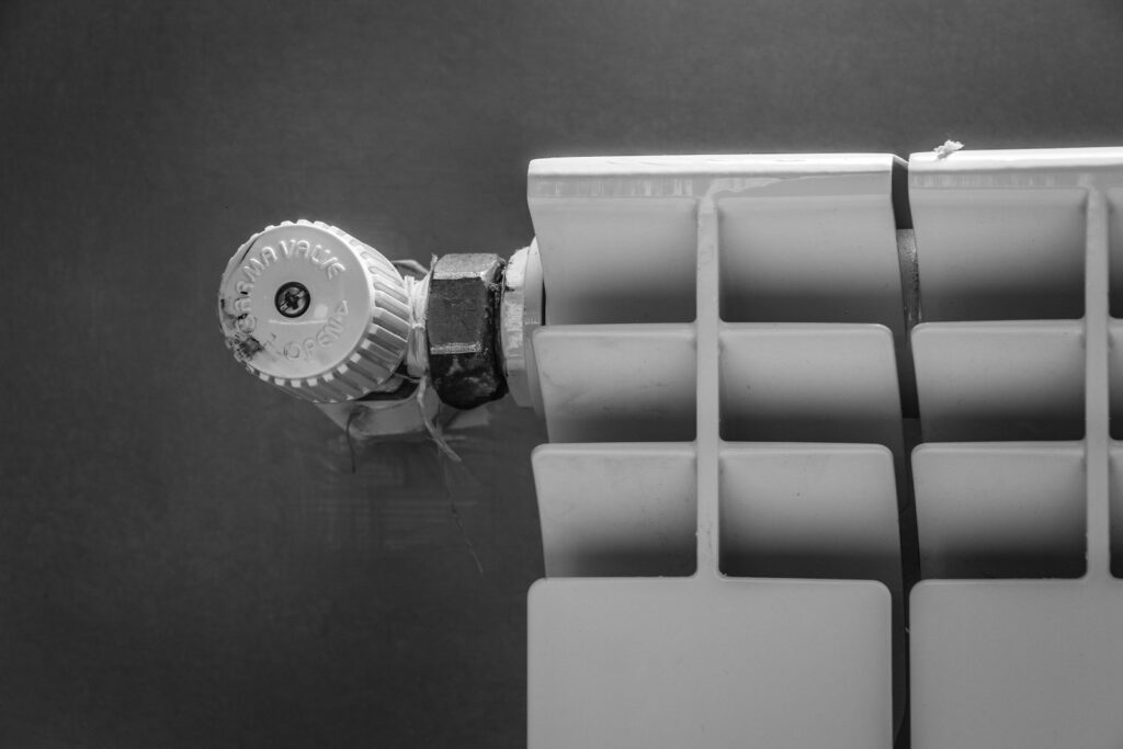 Hand dreht am Thermostat, um Heizkosten sparen zu können