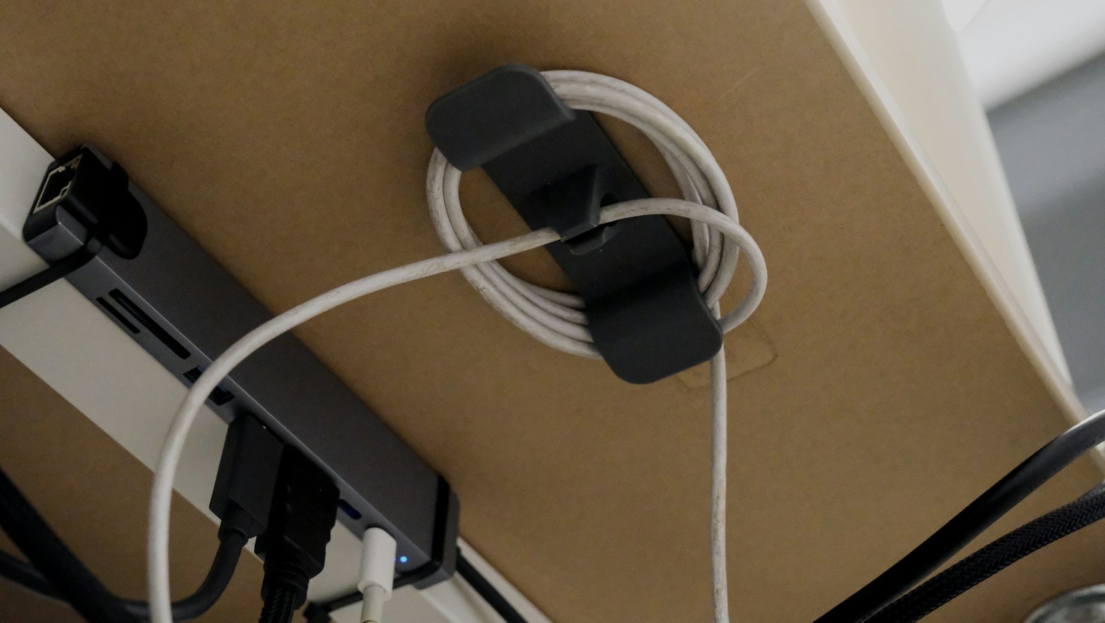 Kabelhalter mit aufgerolltem Kabel unter einem Schreibtisch