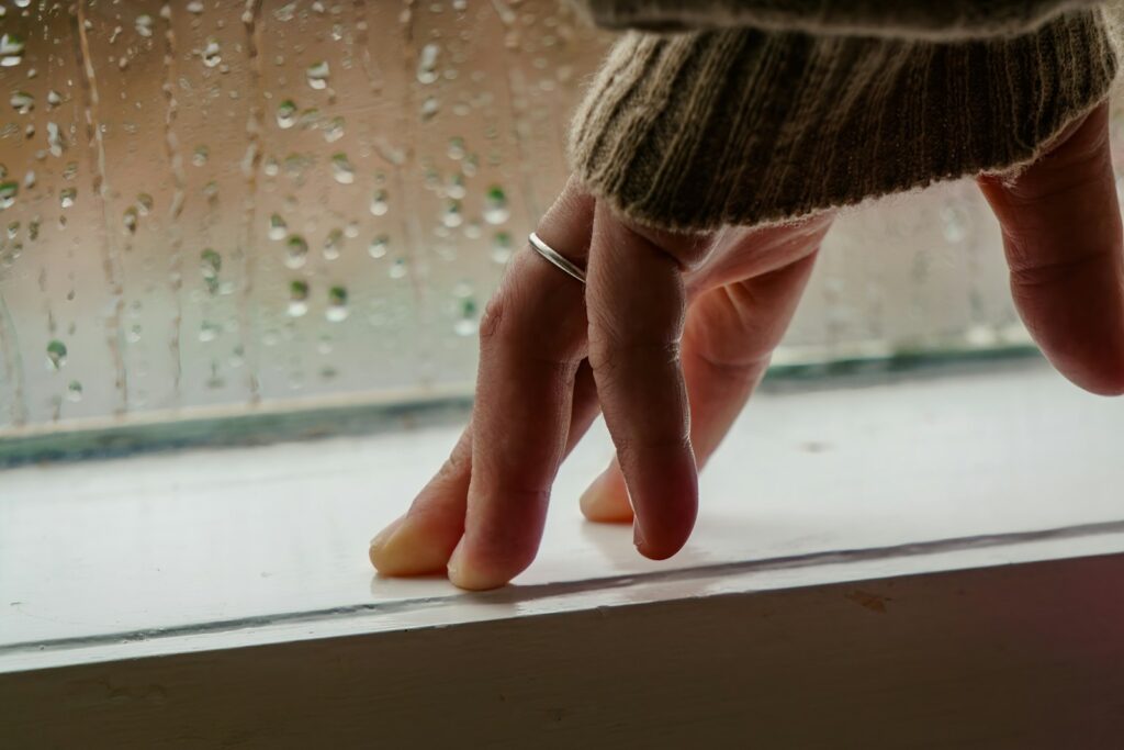 Hand prüft die Dichtung am Fensterrahmen, um die Wohnung winterfest machen zu können